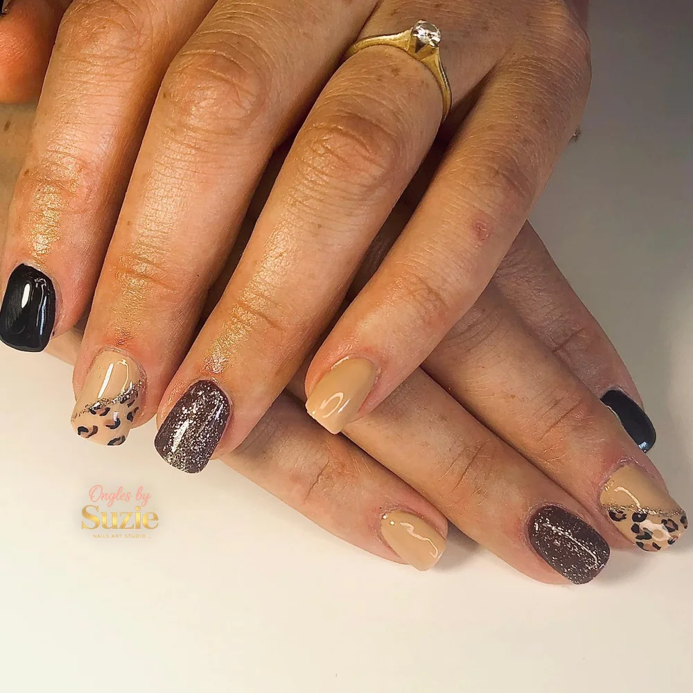 Pose carrée courte mêlant nude, noir brillant, paillettes bronze et motif léopard sur un ongle de chaque main